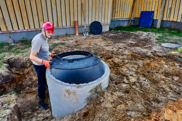 istock Worker installs support ring for septic tank lid onto  concrete well. 2180827695