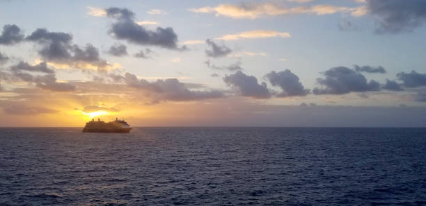 istock Cruise Ship Backlit with Colorful, Dramatic Sunset in Blue Sky with Fluffy Clouds and Dark Sea 2180832567