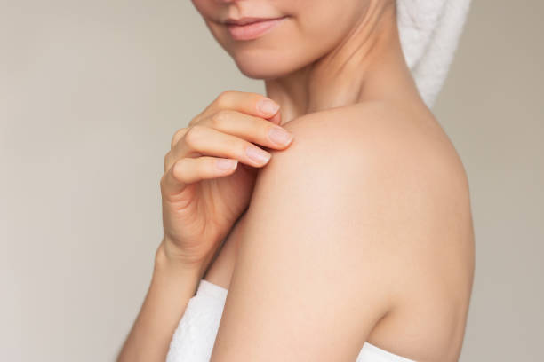 istock Young woman smiling and gently touching her shoulder with her fingertips. 2180839484