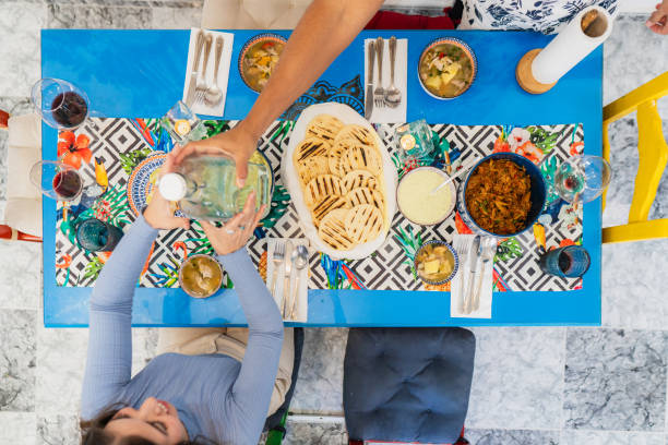 Latin couple having dinner serving water from jar at home