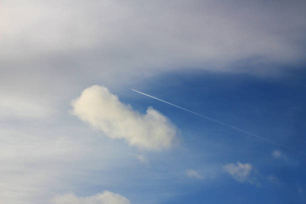 A plane flying high I the sky by the clouds