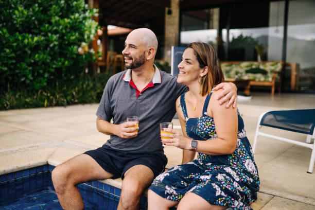 Smiling young couple sitting and having juice in the pool area