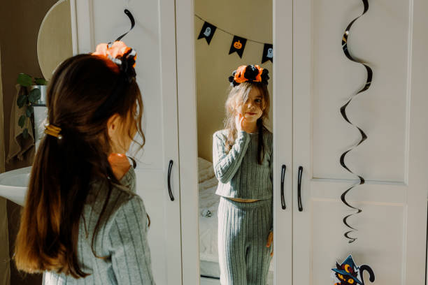 istock A child with a Halloween headband looks in the mirror. 2180858175