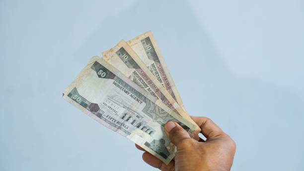 istock hand with holding Saudi Riyal notes isolated on white background 2180861197