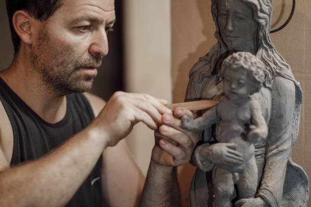 istock Sculptor working meticulously on clay virgina mary sculpture in workshop 2180874488