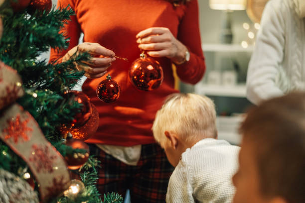 istock Mother hanging christmas baubles while children watch 2180892390