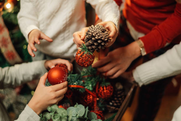 Family decorating christmas tree with red ornaments and pine cones