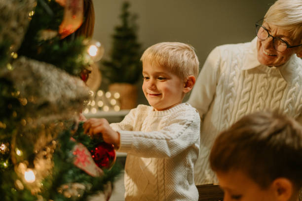 istock Happy boy hanging baubles on christmas tree with family 2180892404