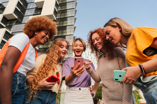 istock Diverse group of young women excitedly using a smartphone outdoors. Friends browsing the internet together, sharing fun content, and enjoying social media on a day in the city, smiling and laughing 2180893237
