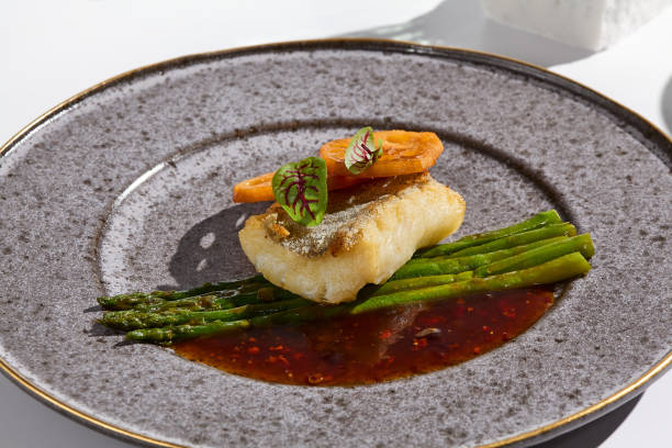 istock Elegant Culinary Art Cod Fillet with Asparagus and Lotus Root in Minimalist Light 2180905702
