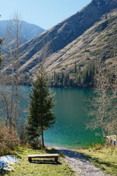 istock Rustic wooden bench overlooking turquoise mountain lake, peaceful rest spot with panoramic alpine views. Kolsai lake, Kazakhstan. 2180911208