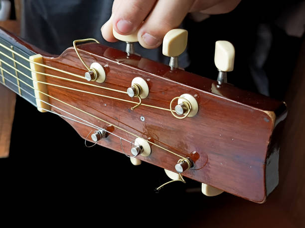 istock The hand adjusts the strings of the guitar. Guitar tuning. The hand pulls the strings of the guitar. Background, place for text. Music lesson concept. Playing the guitar. 2180913474