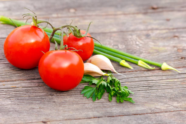 istock Three tomatoes and some green herbs are on a wooden table 2180915901