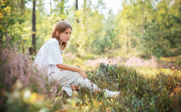 istock A young child sitting quietly in a serene forest, surrounded by vibrant greenery during a sunny afternoon 2180917754