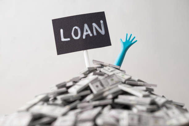 istock Pop out hand from heap US dollar banknotes and LOAN label white wall background. 2180921522
