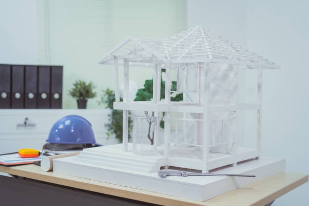 istock A home design company's office with a house sample placed on a desk, showcasing house structure design and drafting plans. The scene focuses on architecture, with no people present. 2180923680