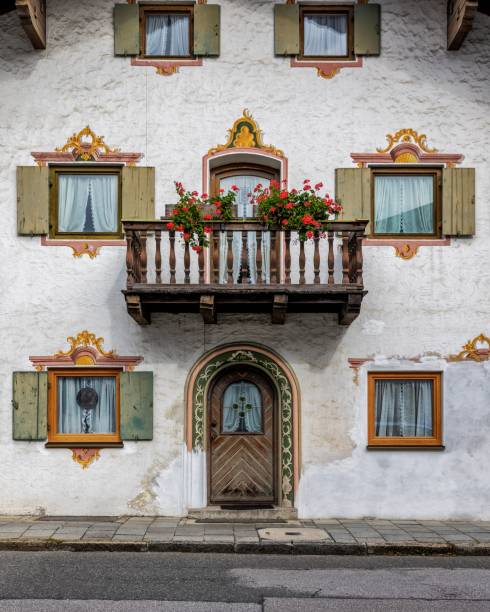 Garmisch, Germany – October 02, 2024: Alpine-style buildings with a wooden door featuring a decorative arch and patterns.