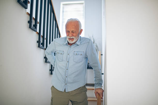istock Senior man comes down the stairs with pain in his back 2180927548