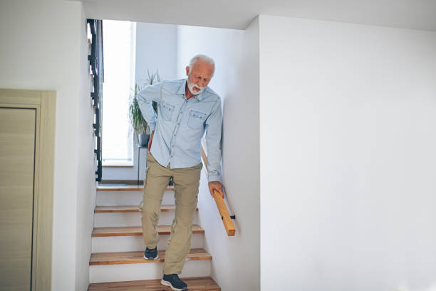 istock Senior man comes down the stairs with pain in his back 2180927952