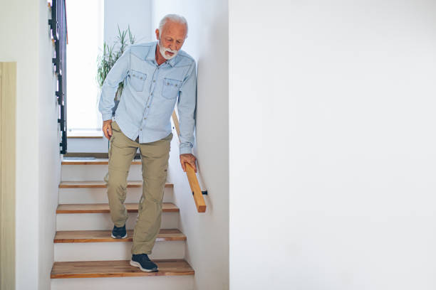 istock Senior man comes down the stairs with pain in his back 2180928064