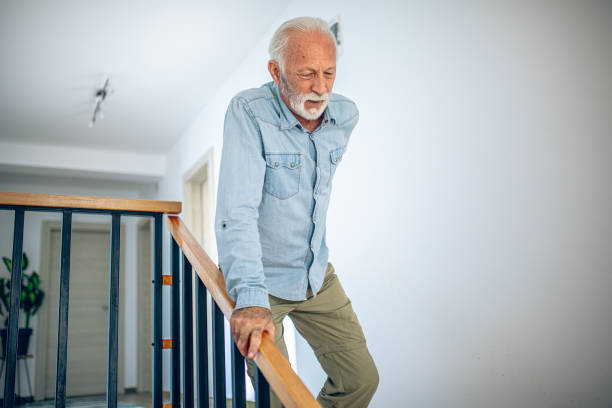 istock Senior man comes down the stairs with pain in his back 2180928139