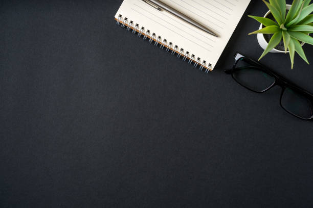 istock Top view of notebook, glasses and ballpoint pen on dark grey background 2180929684