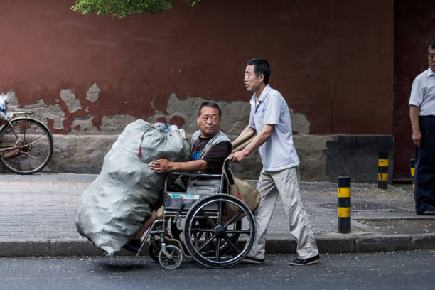 July 5,2014. Two scavengers in the street of the center of Beijing, China. One of them with disabilities. They have no job.