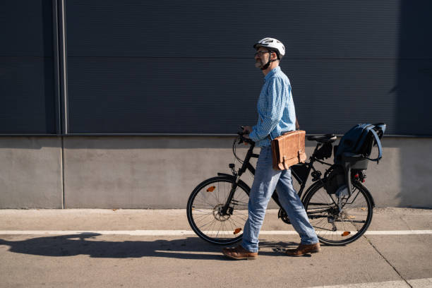 Mid-adult Caucasian man pushing the bicycle, while commuting to the work