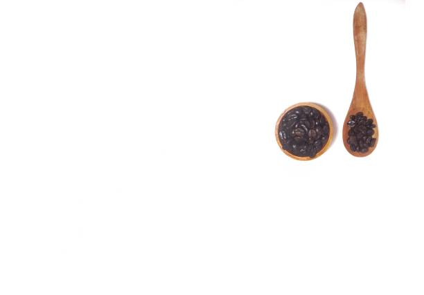 Roasted coffee bean on small wooden bowl and spoon isolated on white background with copy space