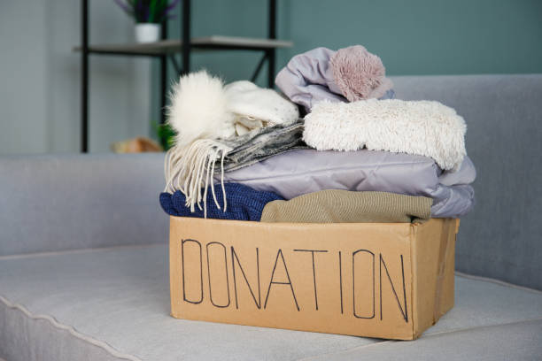 istock Donation box with clothes on the sofa in the living room. 2180944849