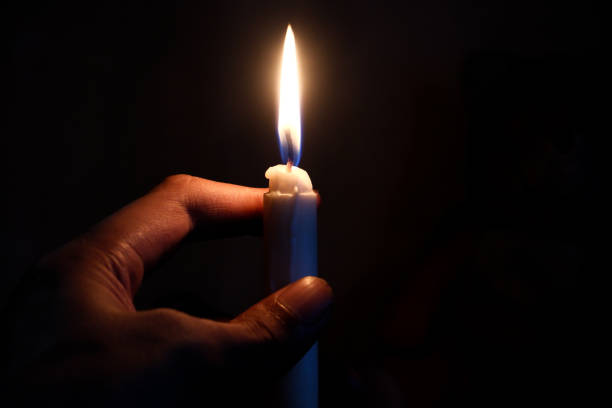 istock Person's hand holding a burning candle in the dark 2180944946