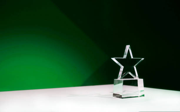 istock Star-shaped crystal prize on a table with green spotlights and copy space 2180945755