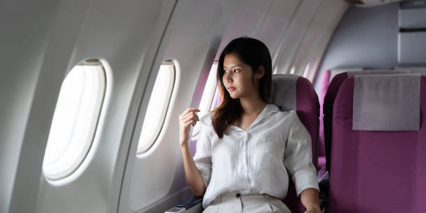 istock Young Woman Sitting by Airplane Window in Comfortable Seat During Flight 2180948299