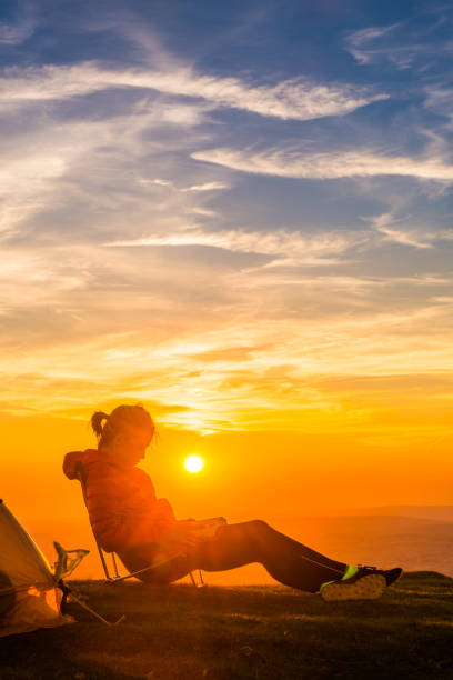 istock Young woman hiker relaxing by tent on mountain at sunset 2180948843