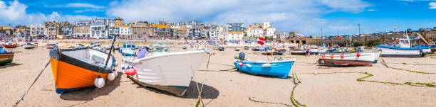 Fishing boats moored on the beach in St. Ives harbour, the picturesque seaside resort and fishing village in Cornwall, UK.