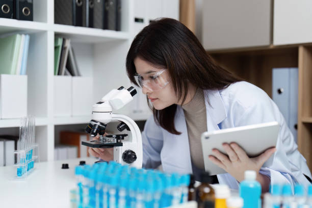 istock Young Female Scientist Using Microscope and Tablet in Modern Laboratory for Research and Analysis 2180951066