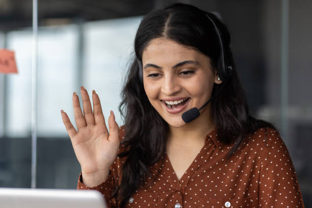 istock Smiling woman in headset waving during virtual meeting in office environment 2180951761
