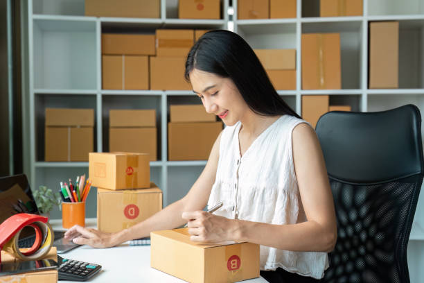 istock Young Entrepreneur Preparing Packages for Online Business Shipment in Modern Office with Shelves of Boxes 2180956209