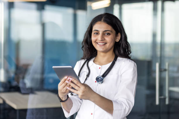 istock Confident female doctor with stethoscope using tablet in modern healthcare facility 2180957014