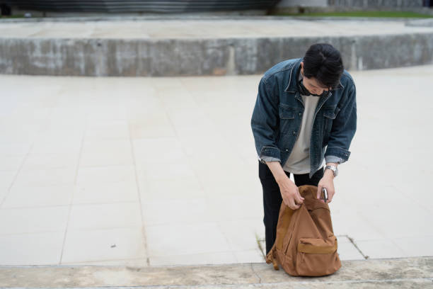 istock Young Student Organizing Backpack Outdoors on Campus in Casual Denim Jacket and White Shirt 2180957025