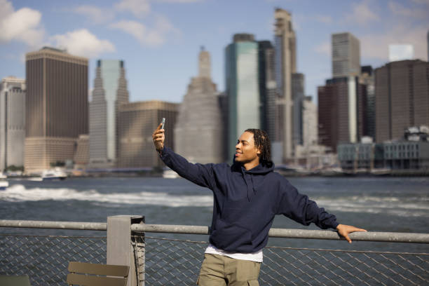 istock Happy black man taking a selfie with mobile phone at riverbank. 2180958315