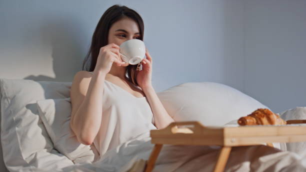 istock Calling lady drinking coffee in bed hotel room closeup. Smiling woman talking 2180958318