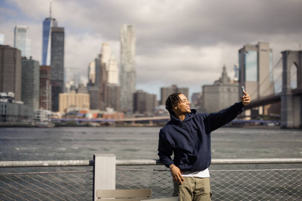 istock Happy African American man taking a selfie with mobile phone by the river. 2180958356