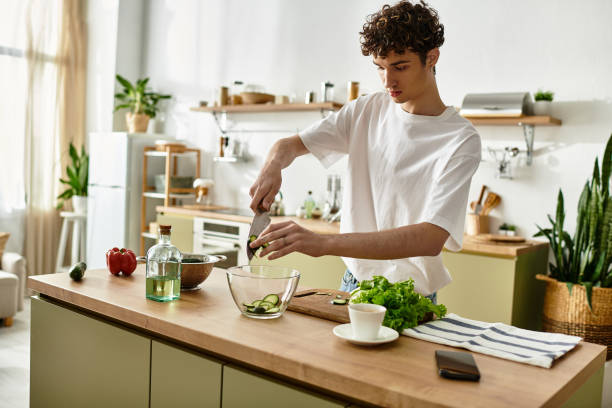 istock Young man with curly hair skillfully preparing a fresh salad in a bright modern kitchen 2180960230