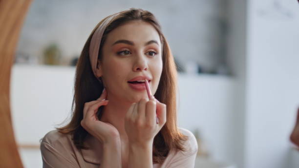 istock Gorgeous woman applying lipstick at morning makeup routine in mirror closeup. 2180960282