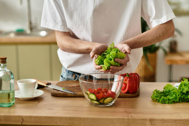 istock A young man makes a fresh salad in a bright, plant-filled kitchen 2180960363