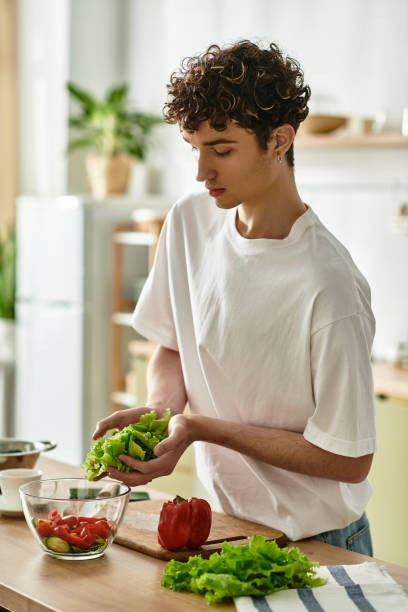 istock Handsome young man with curly hair preparing fresh vegetables in a modern kitchen at home 2180960366