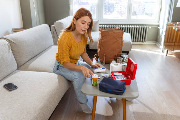 Photo of a woman preparing a survival kit for doomsday A woman carefully selects items like medication, first aid and canned food as part of her survival kit for potential emergencies. earth first aid stock pictures, royalty-free photos & images