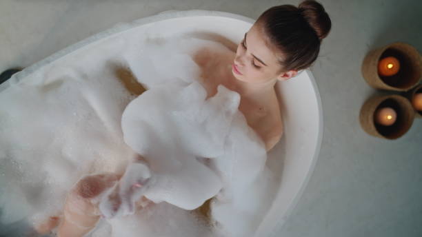 istock Peaceful lady relaxing bubbles bath touching gentle skin top view. Woman lying 2180961102