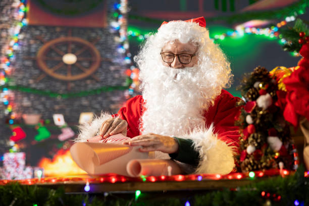 istock Santa Claus in his iconic red suit decorates a Christmas present box 2180962063